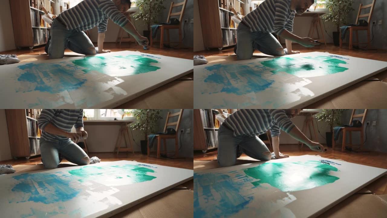 男艺术家从画布上的油漆管中挤压油漆