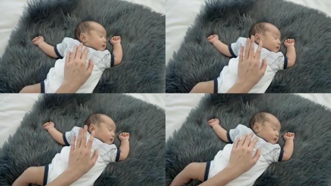 4k，近距离新生儿，2个月大，亚洲人睡在黑灰色的地毯上，母亲的手放在胸前，以使婴儿睡得很好。