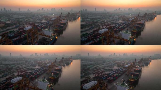 在泰国曼谷的日出场景中，空中无人机拍摄了码头上的一艘货船港口，吊臂下降到适当位置以卸下集装箱