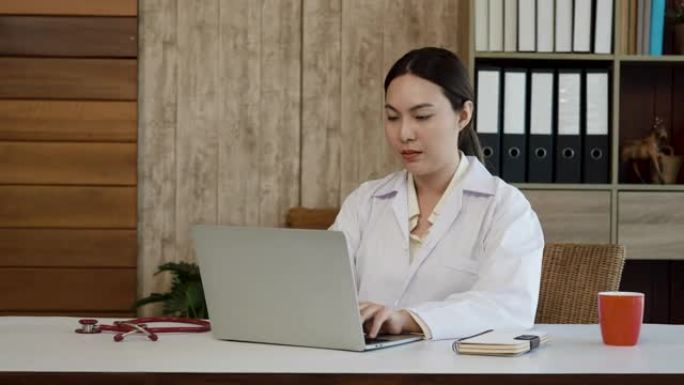 4K，一位年轻的亚洲女医生穿着白色衬衫，坐在办公桌前，拿起听诊器，准备检查病人。