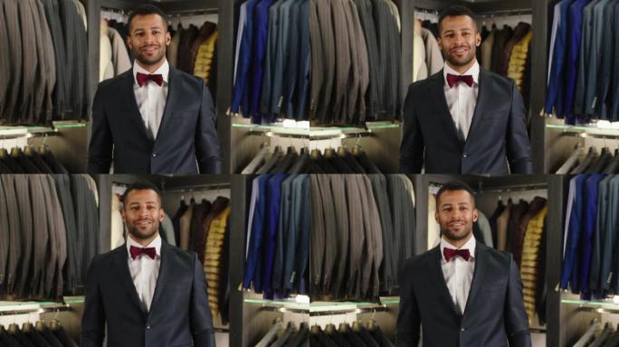 快乐的客户在豪华西装店里的美国黑人男子在镜头前摆姿势，穿着黑色西装，感觉舒适的设计商务和时装理念