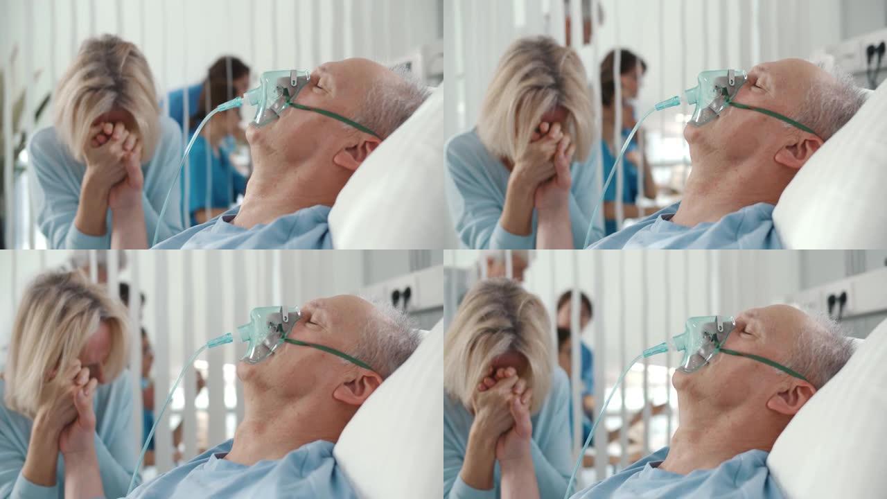 哭泣的女人在医院坐在床上时握着年迈的丈夫病人的手