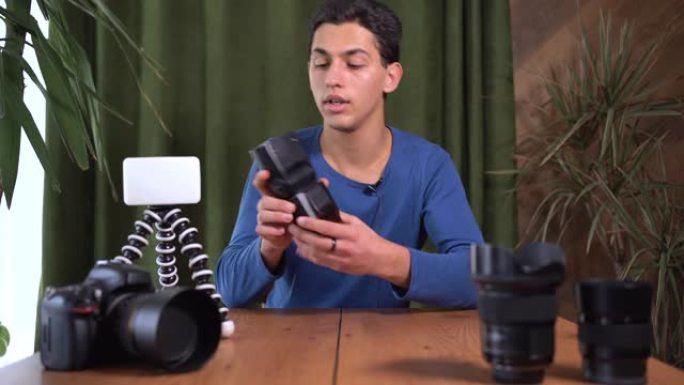 摄影师视频培训，在线课程。一名阿拉伯男子看着相机，谈论使用闪光灯和脉冲光的原理。信息业务和在线销售课