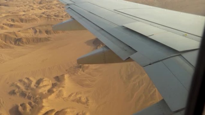 飞机降落在沙漠中，从飞机机翼上的窗户看到的景色，飞机的坠落，飞机的襟翼。飞机失事。