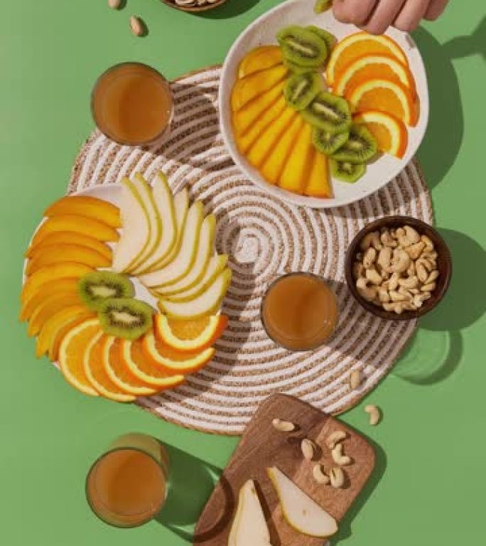 绿色餐桌上的水果坚果零食。人们在一起，吃健康的食物。俯视平面家庭用餐