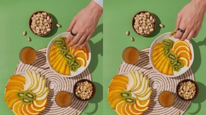 绿色餐桌上的水果坚果零食。人们在一起，吃健康的食物。俯视平面家庭用餐