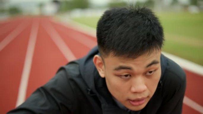 中国年轻人在体育馆的跑道上慢跑时累了。年轻的亚洲男性激烈训练锻炼挑战呼吸疲惫。健康积极的生活方式理念
