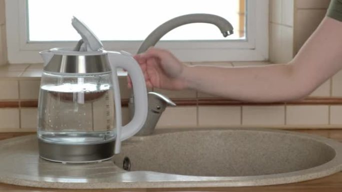 女人用倒入玻璃水壶的过滤水关闭水龙头。水槽有两个水龙头，普通和过滤水。过滤系统或渗透，净水。4k视频