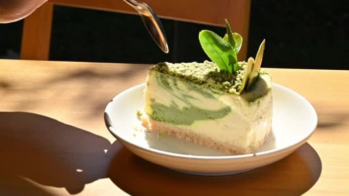 有人在吃饭前用勺子切一块抹茶绿茶蛋糕。