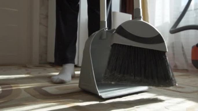 用刷子扫除地板上的灰尘。灰尘上升到空气中。用簸箕扫除地毯上的污垢。打扫房子。做清洁。特写。清洁服务。