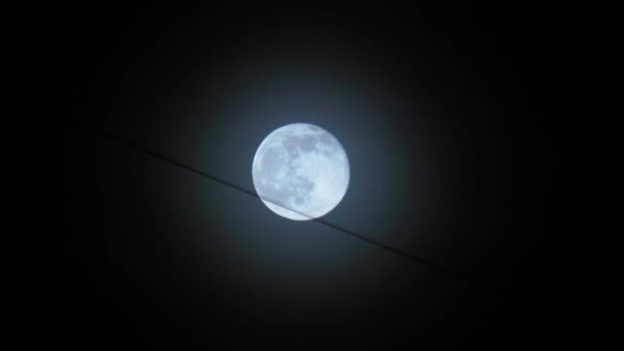 夜黑天空背景下的满月，建筑物上的电线