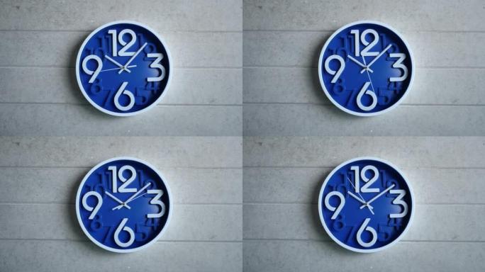 一个蓝色的办公室时钟挂在灰色的混凝土墙上。时间流逝，时间流逝