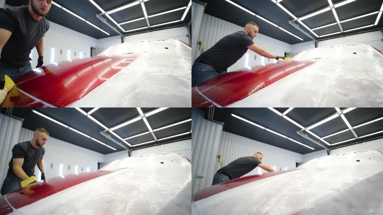 男子工人在洗车场洗红色汽车。