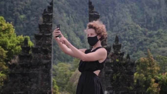 生活方式的女孩博客作者在印度尼西亚Bedugul的传统巴厘岛印度教门Candi Bentar上全黑射