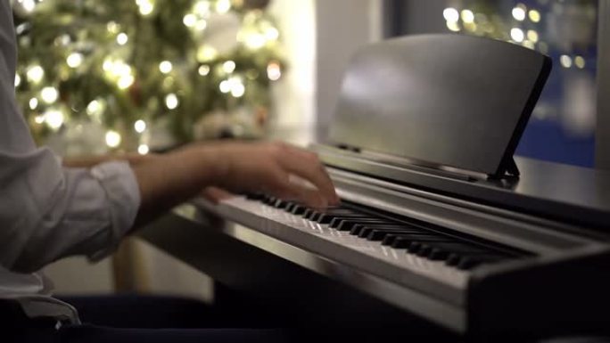 一位钢琴家音乐家在圣诞树旁弹奏数码钢琴
