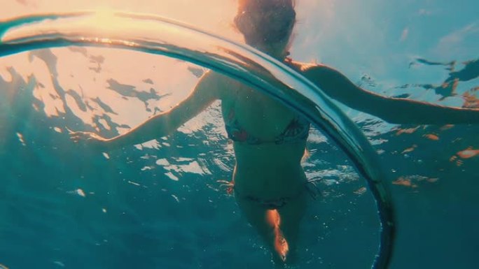 泡泡戒指。女自由潜水者观看水下移动的泡泡戒指
