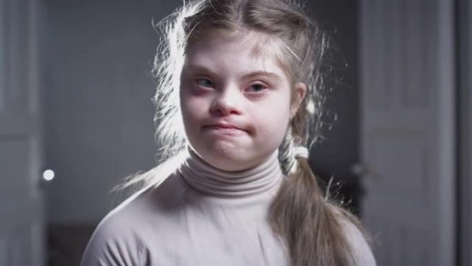 患有唐氏综合症的快乐女孩的肖像。开朗的孩子对着镜头微笑。有特殊需要的人。儿童染色体遗传疾病。