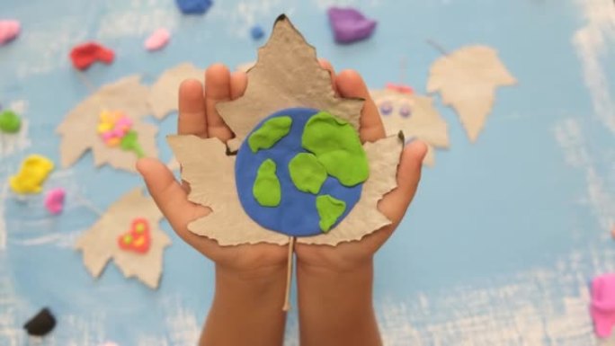 儿童为地球日雕刻橡皮泥行星。保护环境，拯救我们的星球。生态学概念。艺术学习和教育的概念，金砖四国