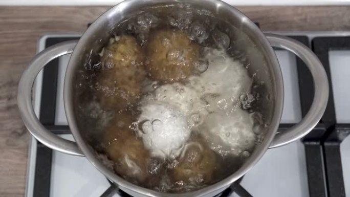 生的白鸡蛋和土豆在厨房的煤气炉上的平底锅中用沸水煮沸。特写。顶视图。烹饪健康食品的概念。4K。