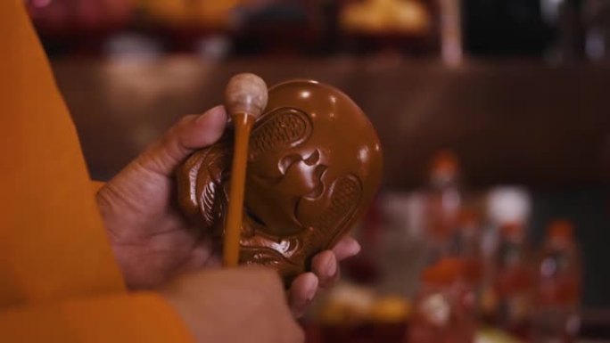 佛教传统乐器，背景为棕色和橙色套装