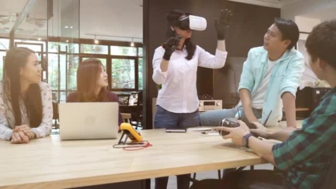 年轻的创意开发人员戴着虚拟现实耳机在笔记本电脑上工作，他们开发新的AG，VR游戏和应用程序。背景时尚