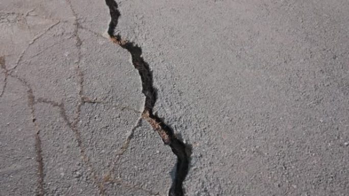 旧公路上的表面破裂，路面上有深断层的裂缝。