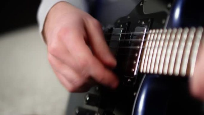 特写创意音乐家在蓝色电吉他上弹奏手指。