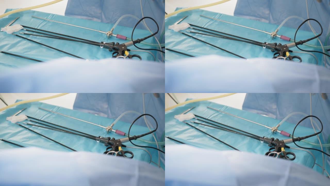 蓝色桌子上的腹腔镜剪刀和抓紧器。多功能腹腔镜器械。用无菌手套将女性手放在腹腔镜手术的套管针上