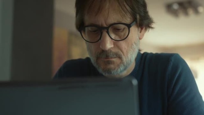 一个认真的中年男子在笔记本电脑上工作。多莉开枪