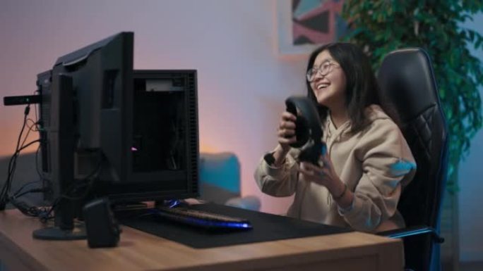 女孩在电脑上玩游戏。Pro gamer赢得圆形互联网冠军的女人举手欢喜，在转椅上旋转着快乐的尖叫声，