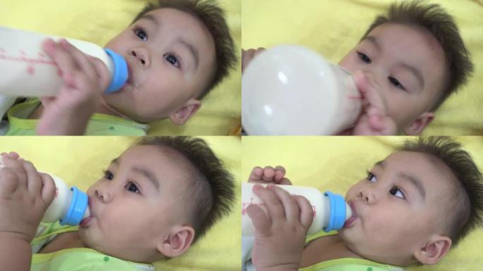 亚洲婴儿在床上喝奶瓶中的牛奶