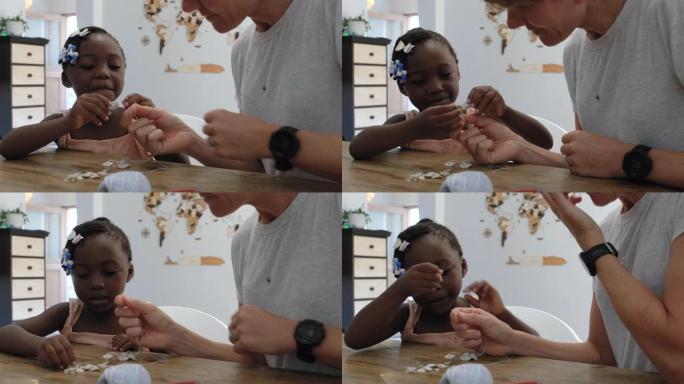 非洲女孩和她更快的母亲一起制作贝壳项链