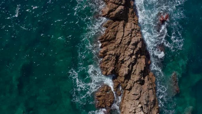无人机航拍，海浪在多岩石的海岸上坠毁。悬崖俯视图