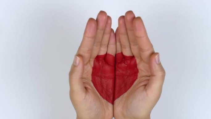 女人的手在视频中露出了手掌心的红色心脏。情人节，爱，信任，帮助，善良的概念。