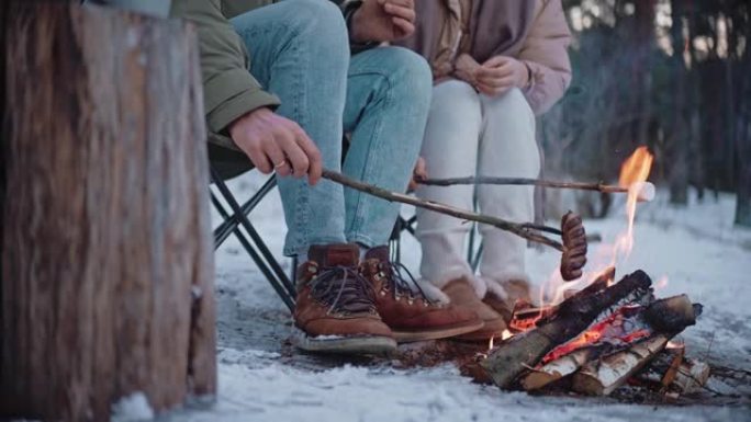 冬天，人们在篝火上用棍子烤香肠和棉花糖