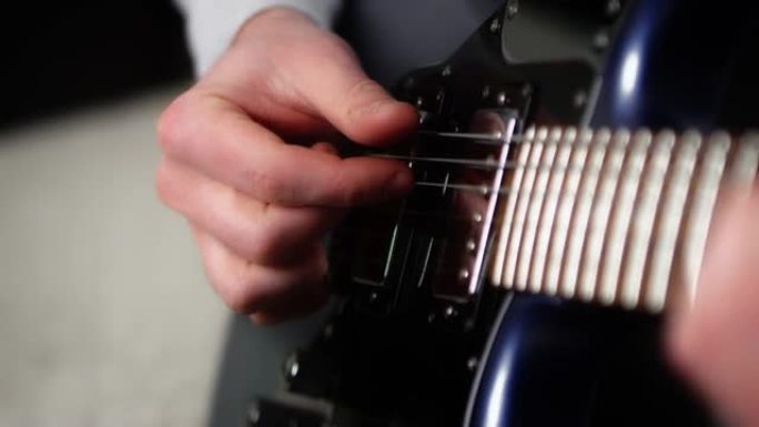 特写创意音乐家在蓝色电吉他上弹奏手指。