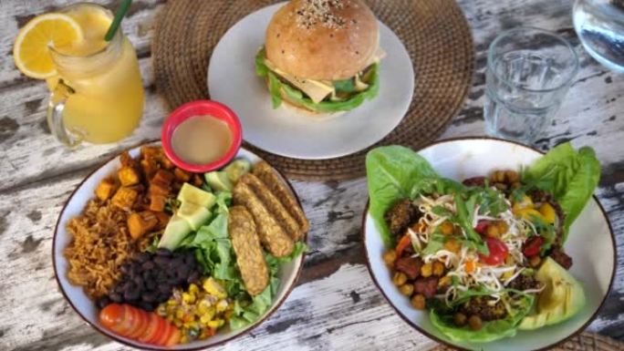 一份健康的早餐，包括各种新鲜蔬菜菜肴、鲜榨橙汁和开胃的素食汉堡，在餐厅的餐桌上等待着您，让您在我们的