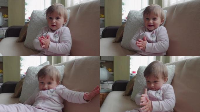 快乐的宝宝坐在家里的沙发上拍手大笑，特写镜头。