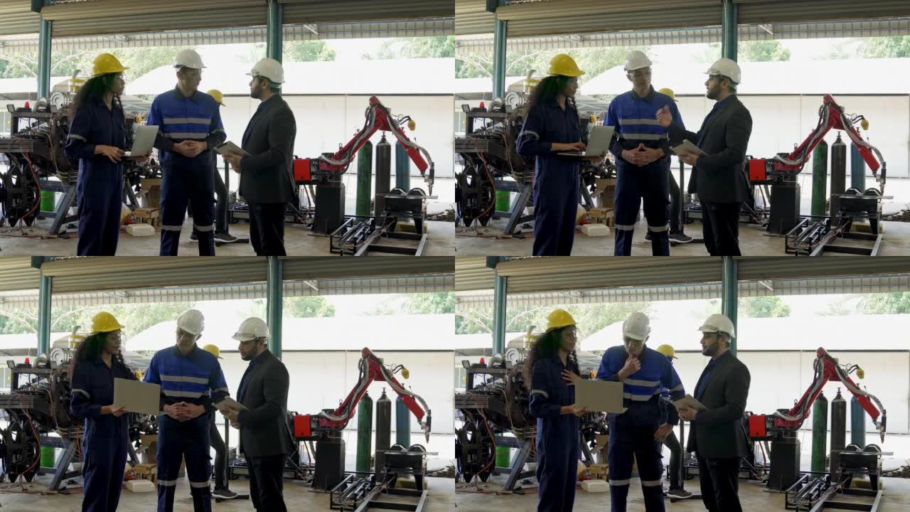 自动化工程师和商人在自动化机器人臂焊接工厂与机器人机器一起工作时咨询蓝领工人