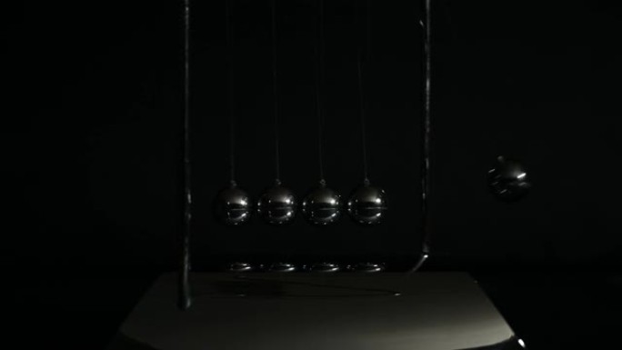 牛顿摇篮平衡球在黑暗的色调。动作和反应，因果的运动物理和通用物理定律概念。牛顿球。