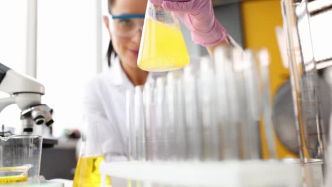 科学家在实验室特写镜头中搅动烧瓶中的黄色油状液体