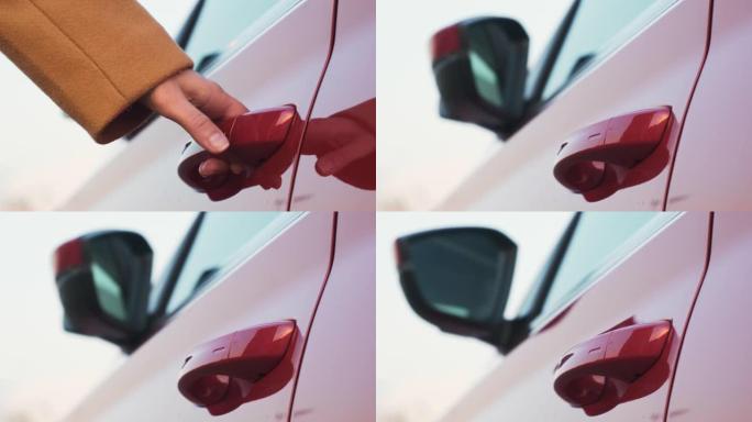 一个女人把手伸到红色的汽车门把手上，打开它，侧镜展开。租车概念