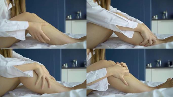 女人坐在床上有小腿腿痛和肌肉腿痛，按摩她的腿，康复后的腿部骨折。医疗保健概念