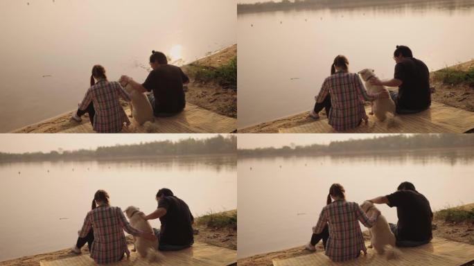 年轻夫妇在海滩上闲逛，和狗一起玩。