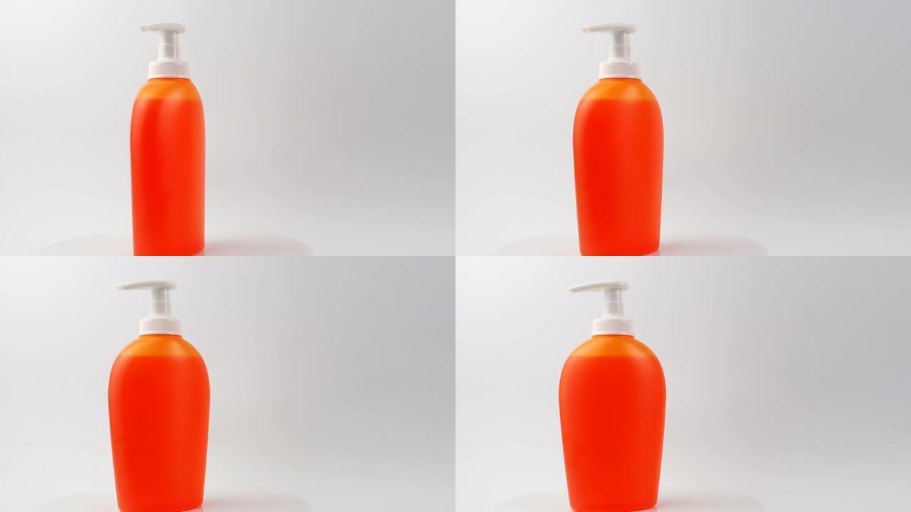 特写，橙色肥皂分配器和液体肥皂。带凝胶的彩色瓶
