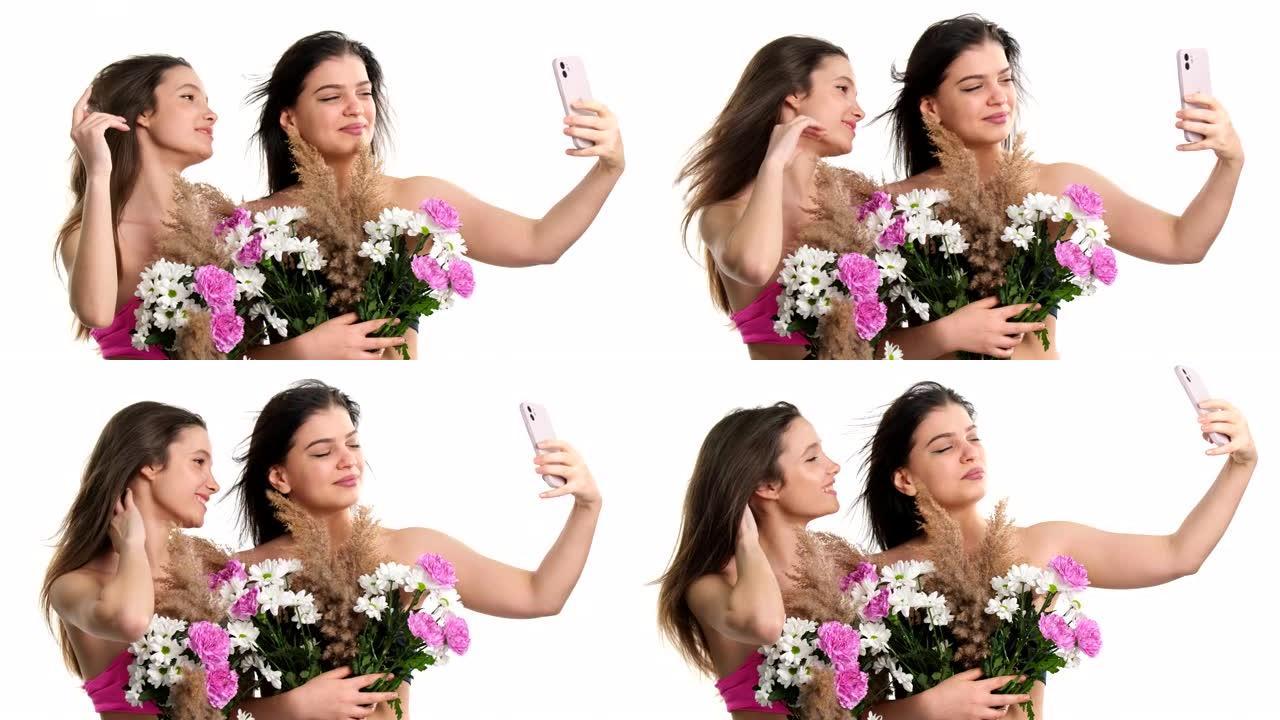 两个漂亮的年轻女人看起来像赤裸裸地躲在花束后面，用智能手机自拍，春天的美丽概念。