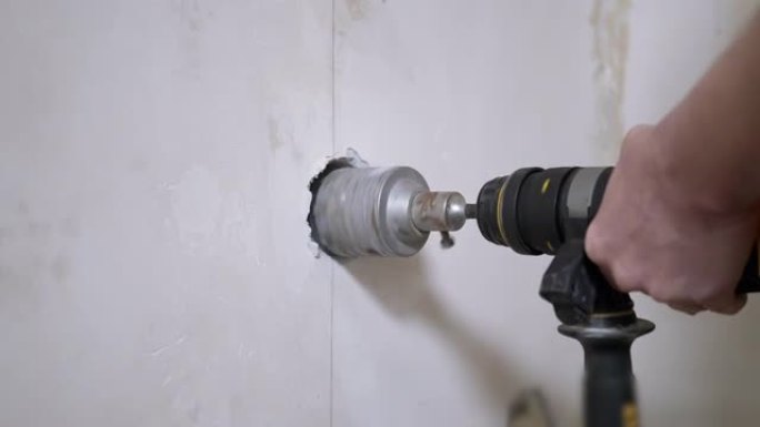 使用打孔机的建筑商在混凝土墙上开一个洞以设置电源插座