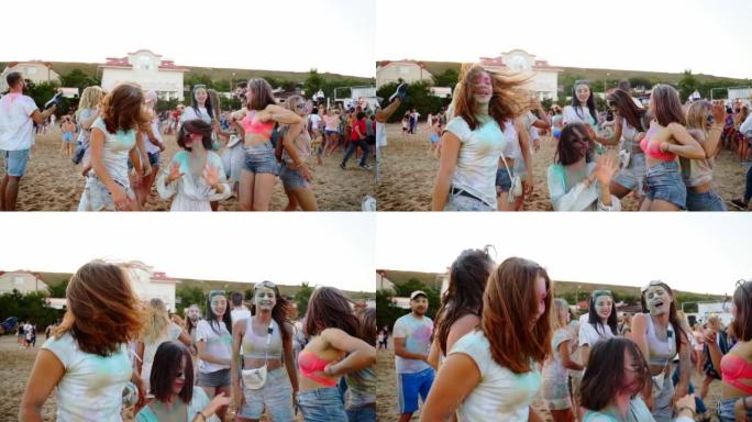 在海滩上的胡里节上，年轻女子以慢动作在沙滩上撒上五颜六色的粉末舞。户外派对。印度教色彩、团结、爱的节