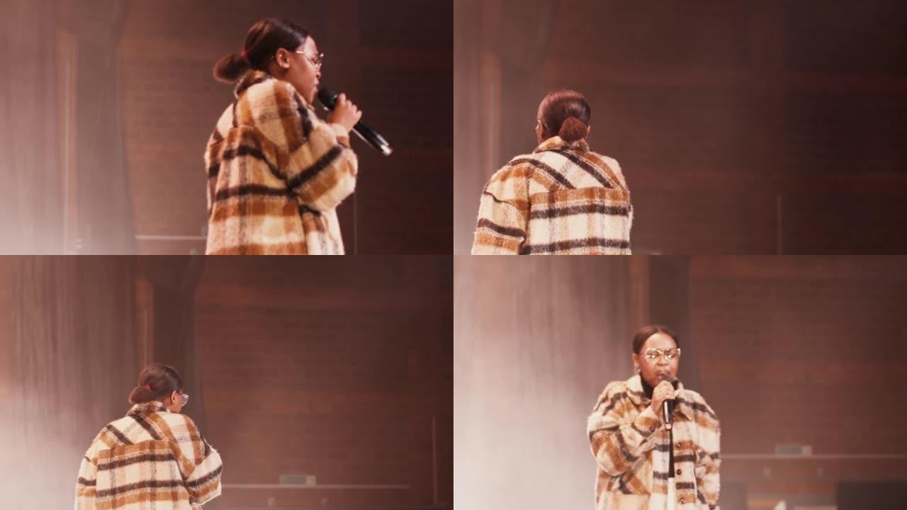 非裔美国妇女在舞台上走来走去时对着麦克风唱歌