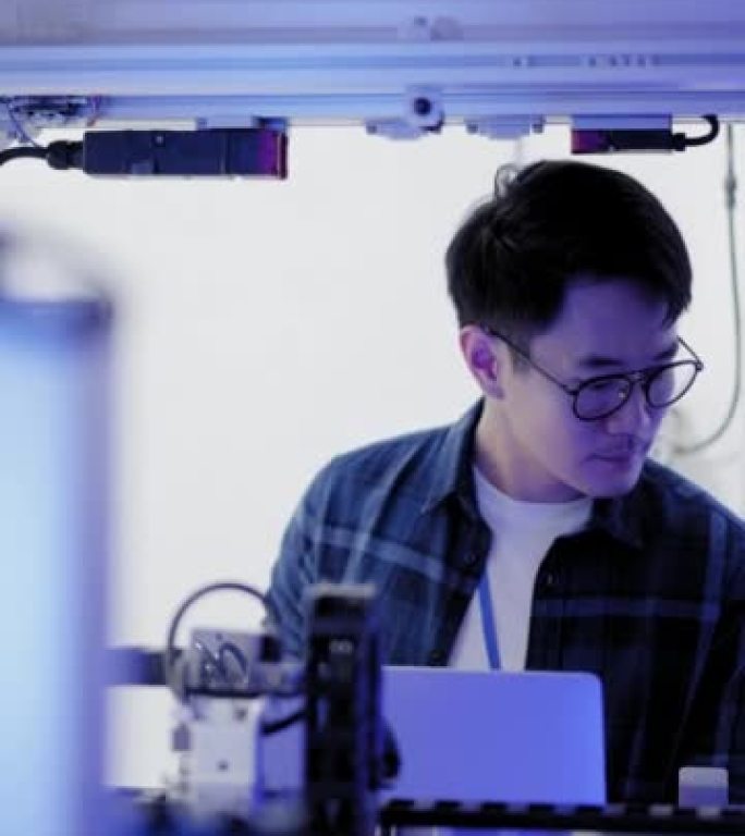 亚洲年轻的机电人工程师通过使用笔记本电脑来检查机器人零件和应用软件的电气系统，以提高自动化生产率。